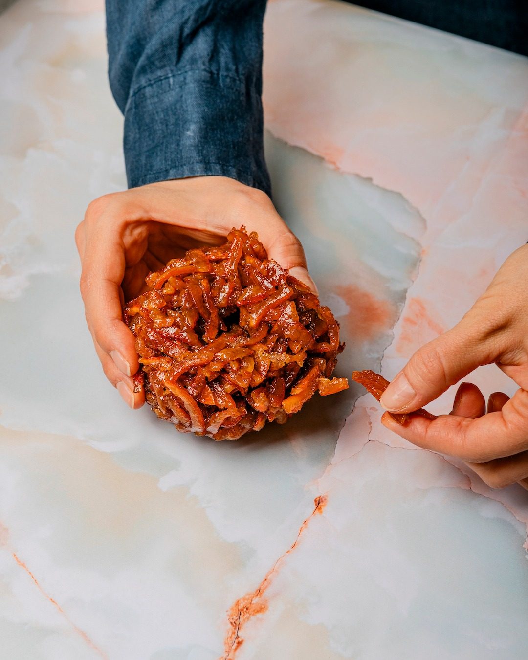 Hands shaping Bonajuto's aranciata, candied orange peel pressed into its nest form