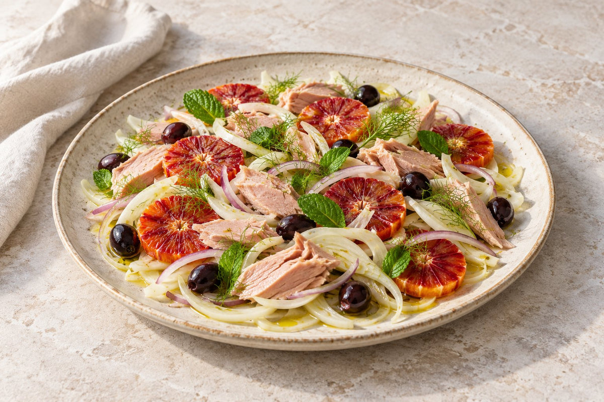Salad of bluefin tuna, blood orange slices, shaved fennel, red onion, black olives and mint on a stoneware plate