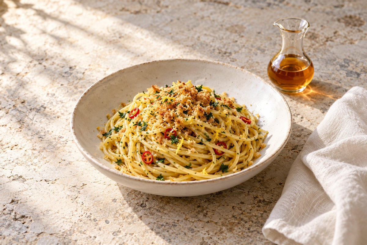 Spaghetti with toasted breadcrumbs, parsley, chilli and lemon zest, a small jug of anchovy colatura beside the bowl