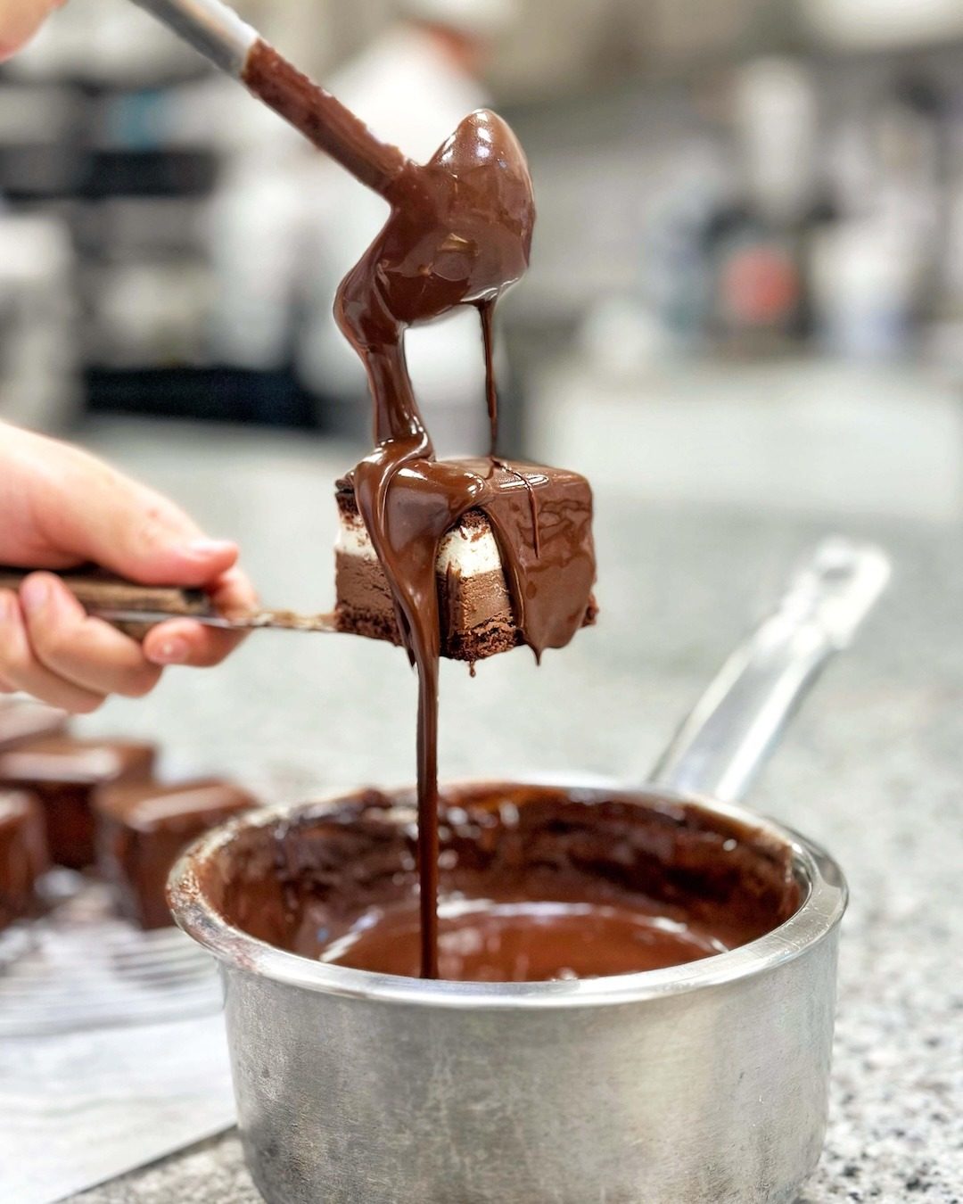 Melted chocolate poured by hand over a sweet in the Bonajuto laboratory