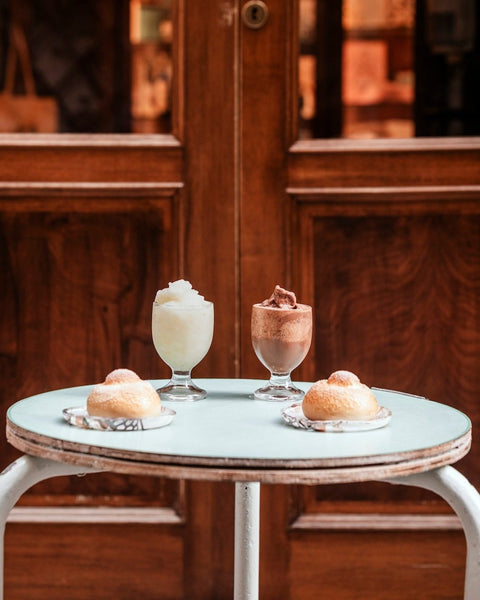 Granitas and brioche on a marble cafe table in front of the wooden doors of the Bonajuto shop