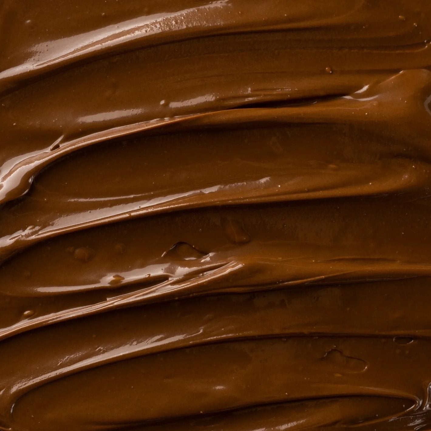 The surface of BonCrem gianduja cream, warm brown and glossy.