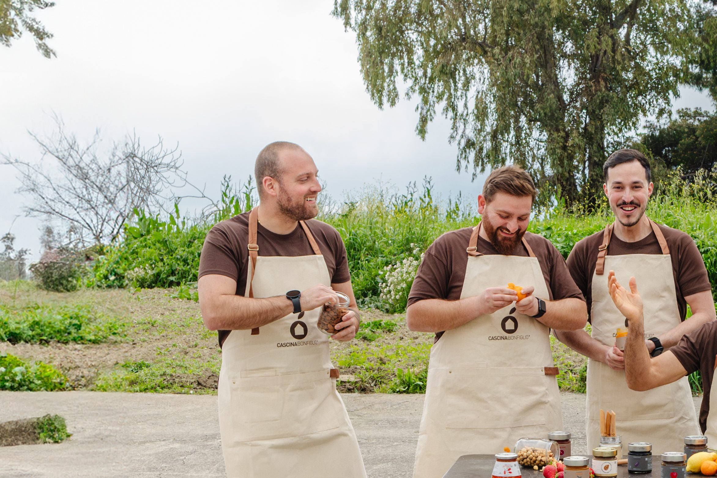 Three of the Cascina Bonfiglio team laughing together in their aprons