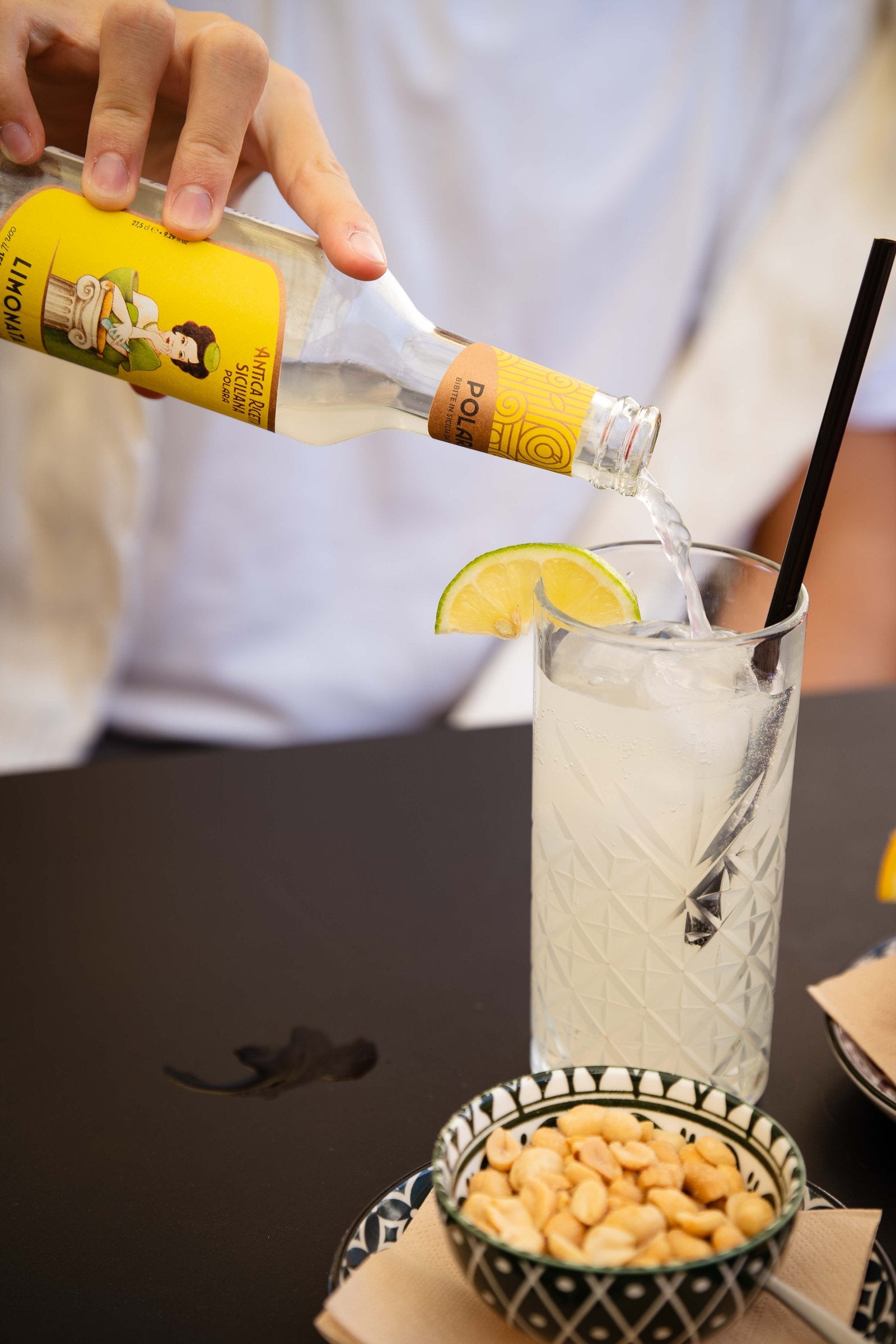 Polara Limonata being poured into a glass with a slice of lime