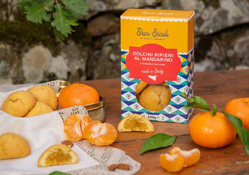 A box of mandarin pastries, whole and halved pastries with an orange filling, and mandarins on a wooden table